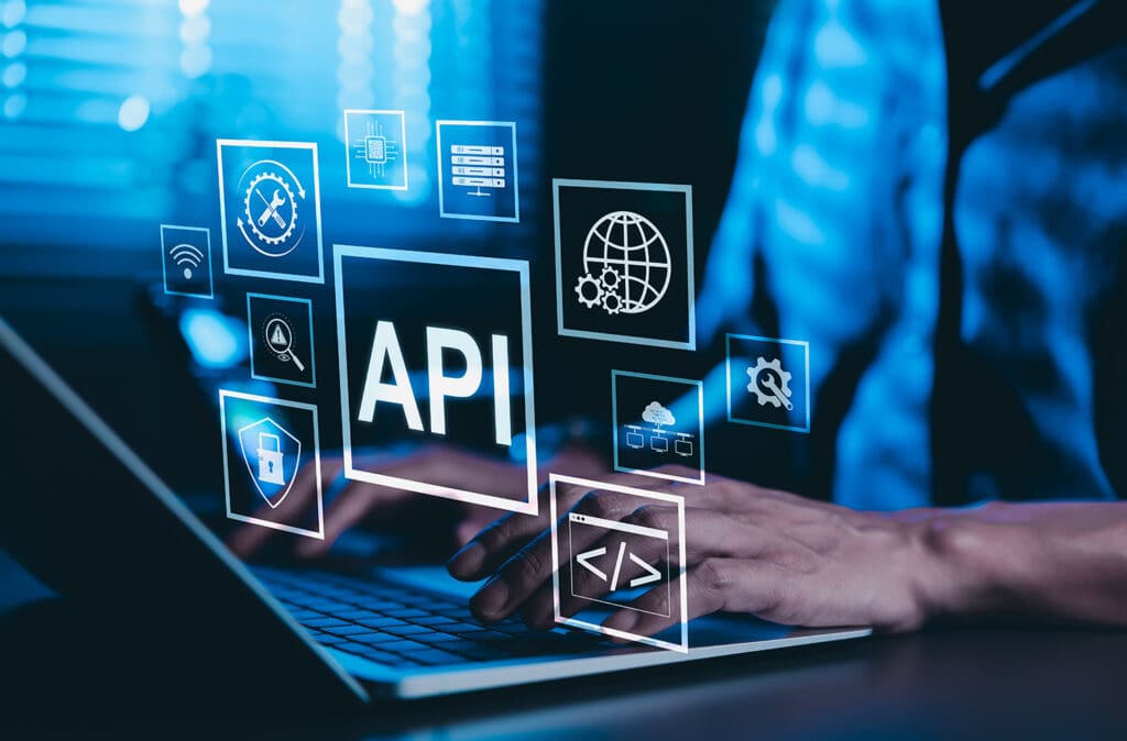 Hands typing on a laptop with virtual API interface icons representing software integration and development tools.